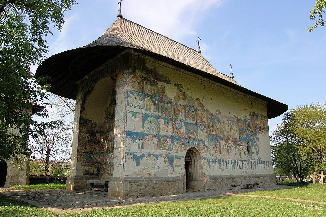 Painted church at Arbore Monastery under a blue sky.