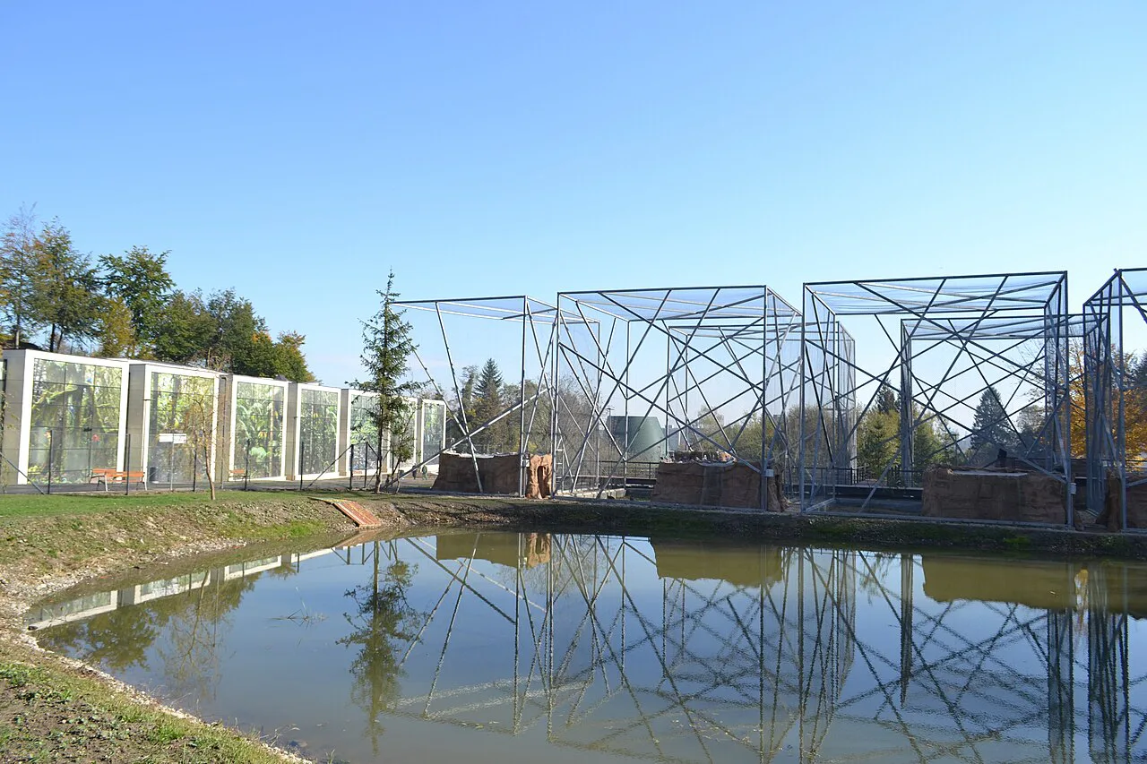 Aviaries reflected in a pond at Brașov Zoo.