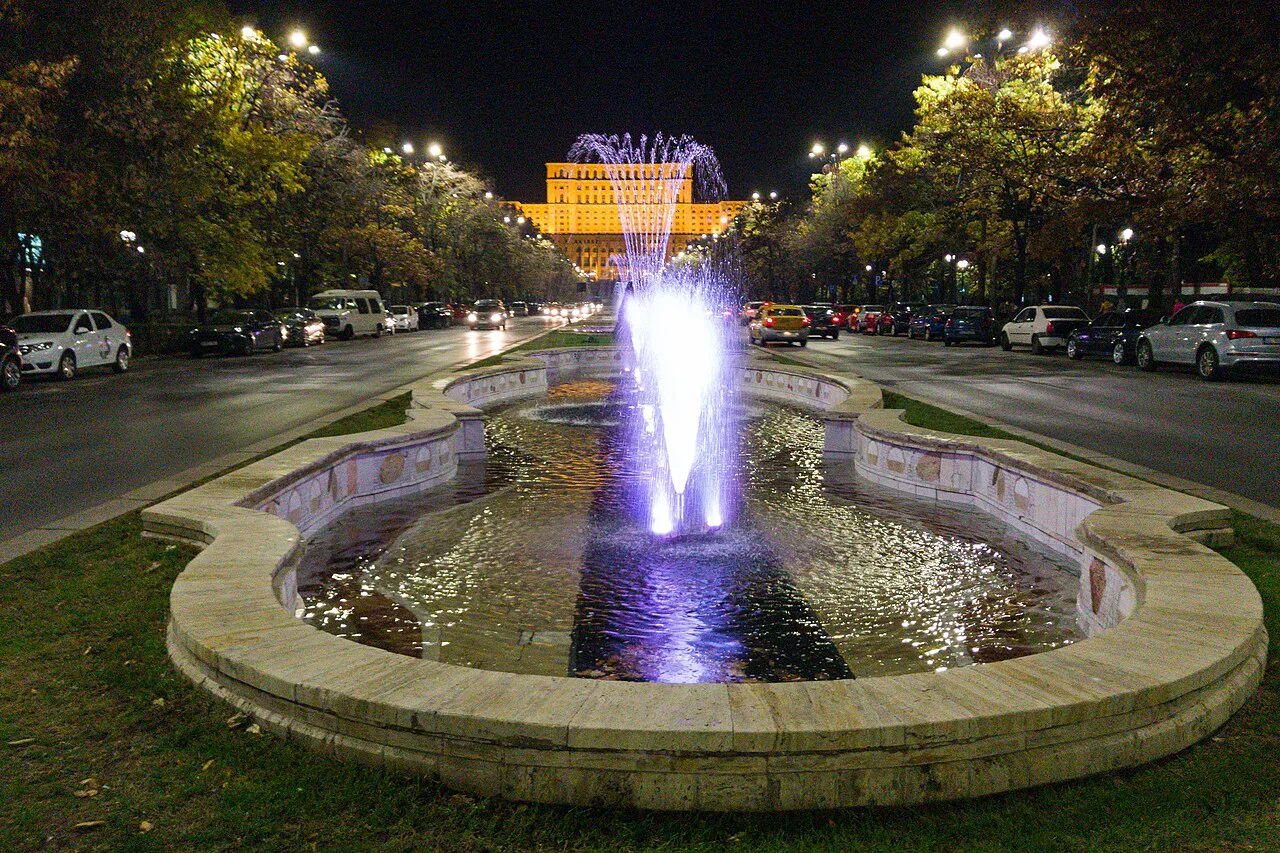 Illuminated fountain in front of the Palace of the Parliament in Bucharest at night.