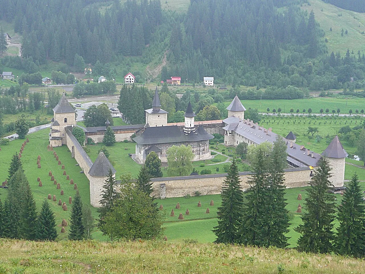 Sucevița Monastery and its fortified walls seen from the hillside above.
